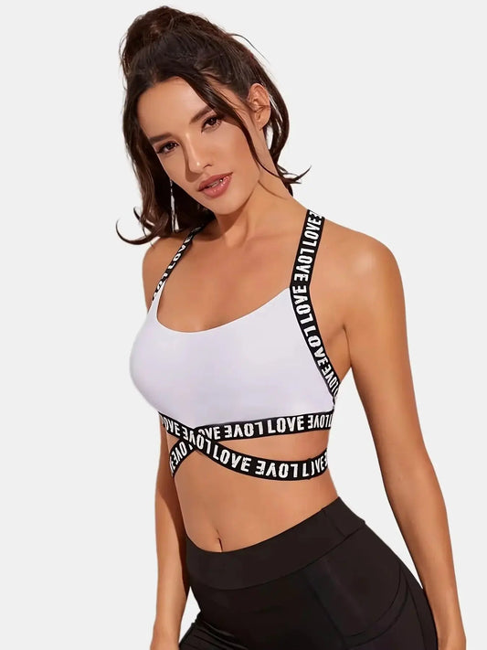 Woman modeling white sports bra with black 'LOVE' straps, black leggings, on white background, OurLum.com